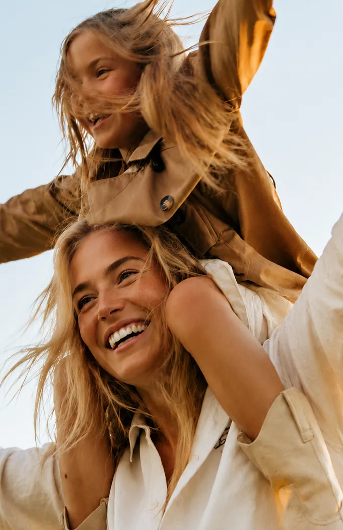 Madre e hija sonriendo al aire libre en un entorno privado